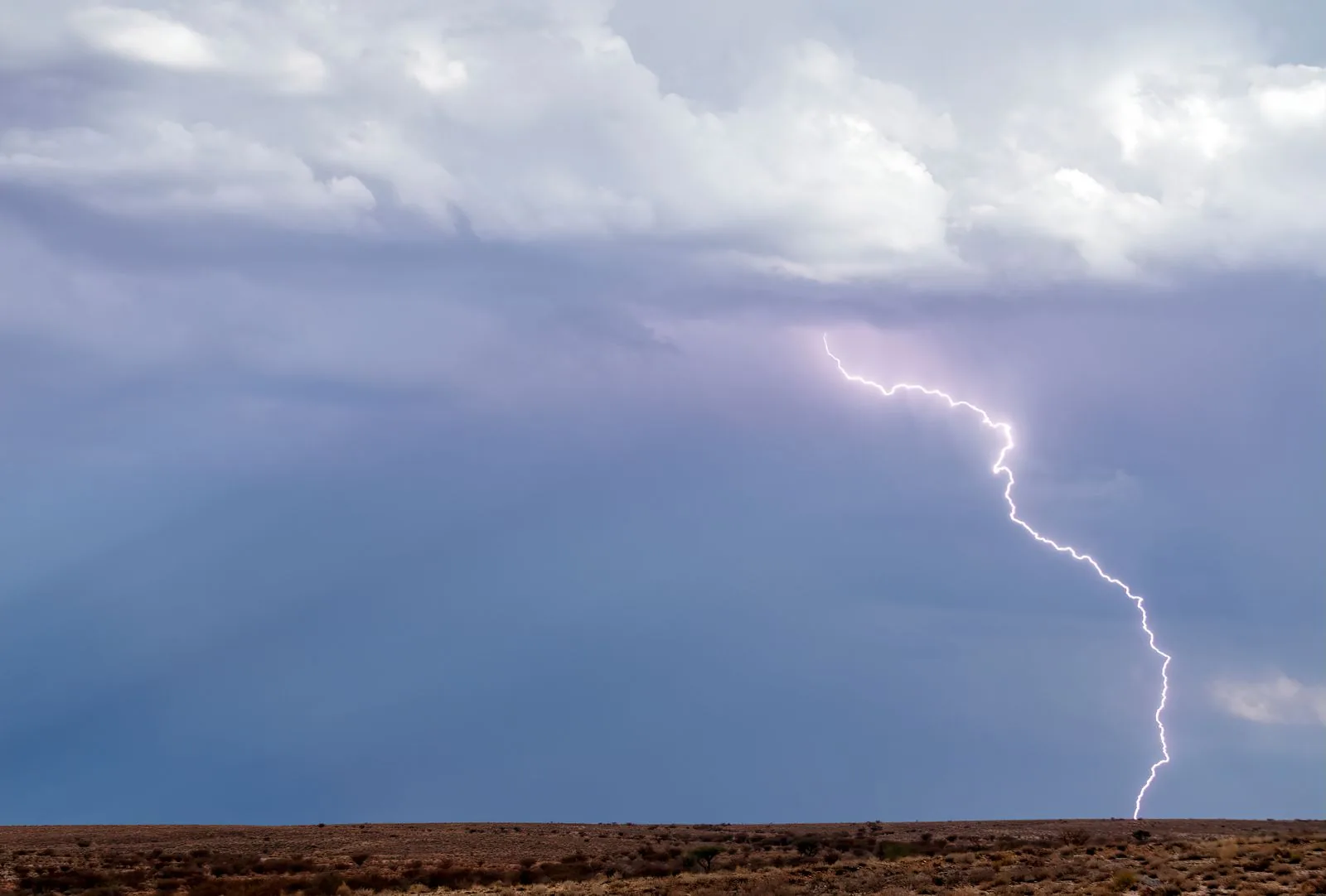 A vivid lightning bolt over a barren desert landscape