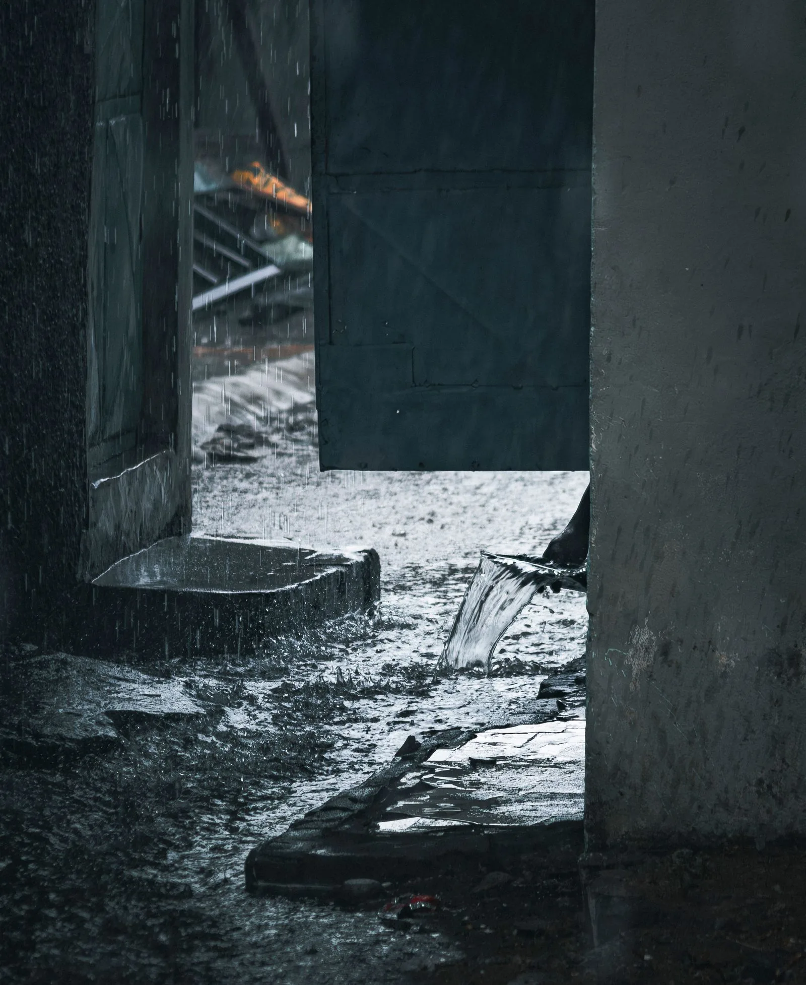 Rainwater streaming from a pipe at a house entrance during a storm